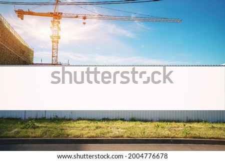 White blank hoarding poster with mockup space on construction site under blue sky
