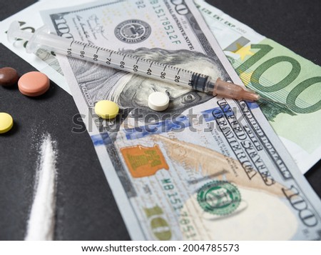 on a black background are dollar bills and various types of drugs, a syringe, powder, pills. The concept of illegal drug trafficking, prohibited means that are life-threatening and addictive.