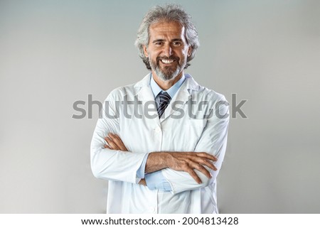 Portrait of confident male doctor standing arms crossed in hospital. Doctor senior man, medical professional with crossed arms confident and happy with a big natural smile laughing at hospital