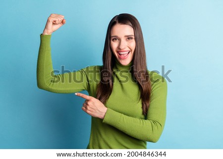 Photo of excited sporty lady show muscle direct finger hand wear green turtleneck isolated on blue background