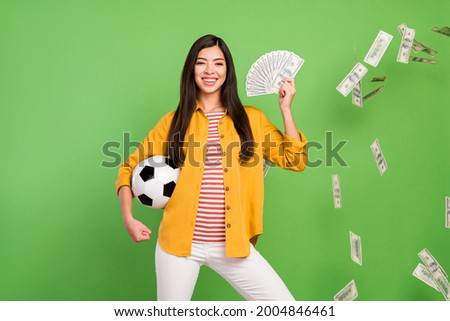 Photo of hooray brunette hairdo young lady hold ball money wear yellow shirt isolated on pastel green color background