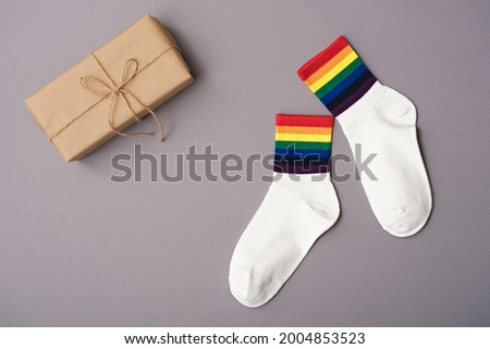 pair of white socks with rainbow edging and gift box on gray background, idea for gift lgbt friends, top view