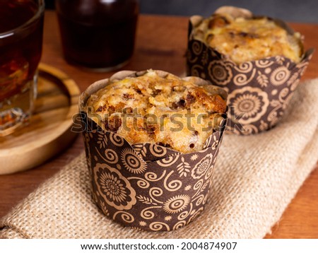 Banana muffin cakes with a cup of iced coffee placed on a wooden table with black dark background