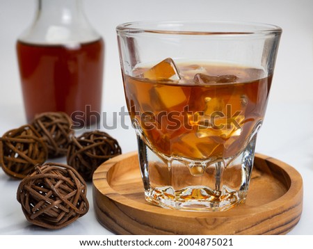 A cup of iced coffee on a wooden table with a jar container. Shoot on dark mood style