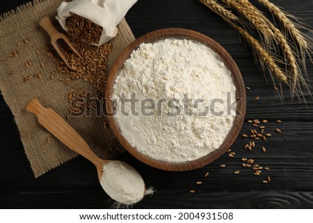 Flat lay composition with wheat flour on black wooden table Royalty-Free Stock Photo #2004931508