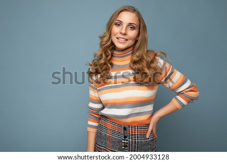 Photo portrait of young beautiful nice positive smiling blonde woman wearing striped pullover isolated over blue background with copy space
