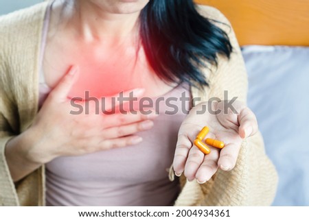 woman taking turmeric pill, or curcumin herb medicine for GERD, treatment for heartburn from acid reflux disease Royalty-Free Stock Photo #2004934361