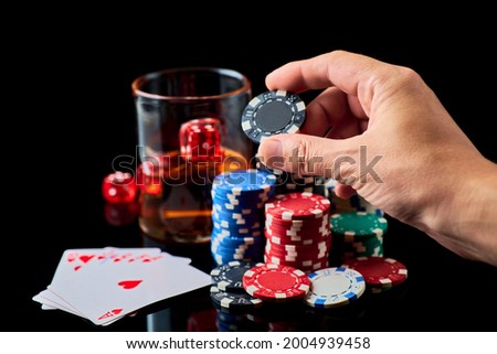 Casino chips, playing cards, glass of whiskey and dices on dark reflective background