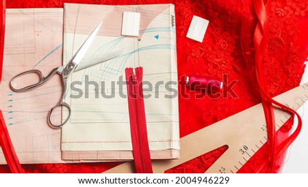 Sewing accessories. Clothes designer work desk. Pattern, scissors, thread,red textile, fabric on white background