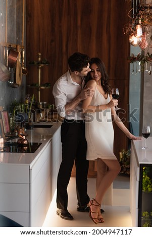 man seducing smiling girlfriend in slip dress with glass of wine Royalty-Free Stock Photo #2004947117