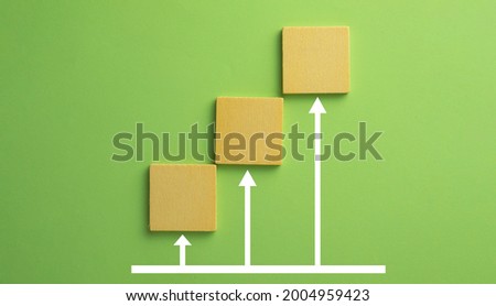 Minimal Wooden block with growing graph over green pastel background with copyspace use for Business development growing growth concept.