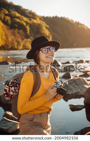 Young woman traveler is taking pictures of nature on retro camera