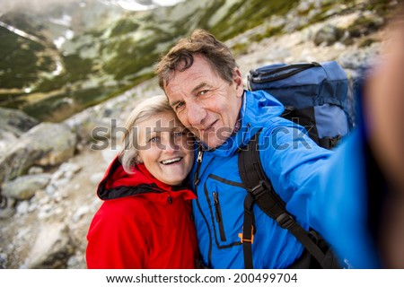 Senior tourist couple hiking and taking selfie at the beautiful mountains