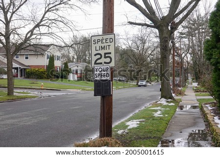 A 25 mile per hour speed limit sign on a wooden utility pole on the side of a community street