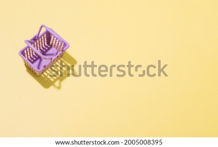Miniature shopping basket in a supermarket on a yellow background. Minimalistic shopping concept with copy space 