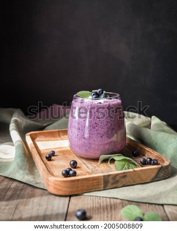 Blueberry smoothie on a wooden salver and black background with a copy space .  Bilberry smoothie low key . Whortleberry smoothie on a green napkin and wooden table. Very peri .  Royalty-Free Stock Photo #2005008809