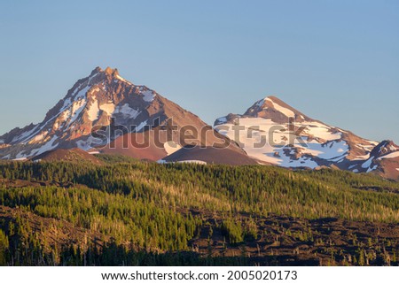 USA, Oregon. Three Sisters Wilderness, North (left) and Middle Sister (right) rise above conifers and lava flow in evening near McKenzie Pass. Royalty-Free Stock Photo #2005020173