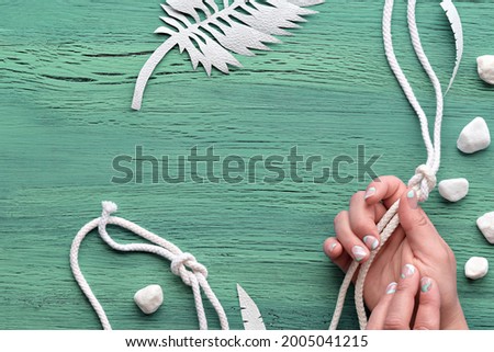 Abstract grungy mint green wooden background with exotic paper leaves made of paper and white stones. Copy-space, place for your text. Flat lay, top view from above.