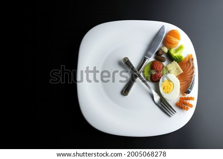a plate simulating a clock with the hands of a fork and a knife showing food, concept of intermittent fasting Royalty-Free Stock Photo #2005068278
