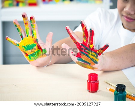 A disabled child in the wheelchair is showing his hands painted proudly in the spacial classroom. Royalty-Free Stock Photo #2005127927