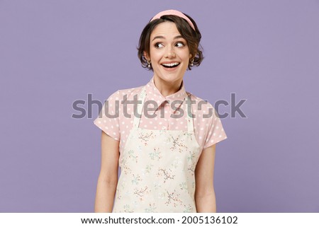 Young amazed impressed happy caucasian housewife housekeeper chef cook baker woman wear pink apron t-shirt looking aside isolated on pastel violet color background studio portrait Cooking food concept