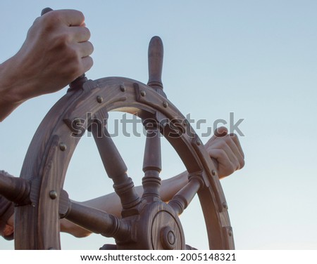Steering hand wheel ship on sky background, hand hold hand wheel Royalty-Free Stock Photo #2005148321