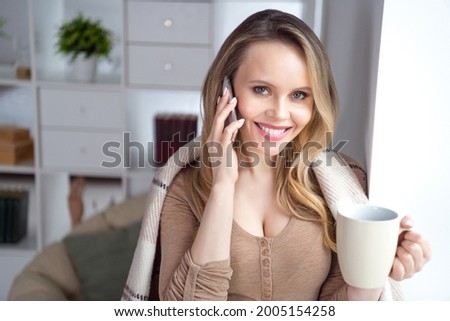 Photo of charming lady hold cup drink coffee make phone call covered plaid wear beige shirt in cozy room indoors