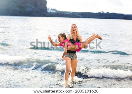 Family holiday on Tenerife, Spain, Europe. Mother and daughter outdoors on ocean. Portrait travel tourists - mom with child. Positive human emotions, active lifestyles. Happy young family on sea beach