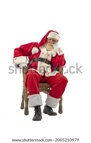 Santa Claus on white background isolated. Senior male actor old man with a real white beard in the role of Father Christmas sitting in a wicker willow chair.