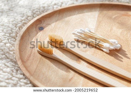daily human hygiene, cotton swabs and cotton pads, a woman's hand holding bamboo toothbrushes on a light background in a glass or against the background of a wooden tray, eco-friendly personal hygiene