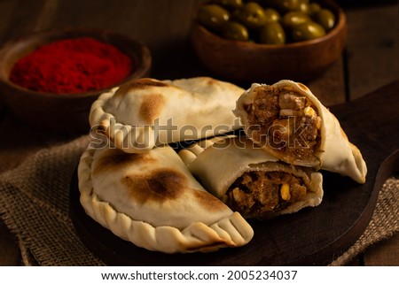 Rich Argentine empanadas in a still-life environment, wooden background, with olives, pepper and paprika. Kitchen concept Royalty-Free Stock Photo #2005234037