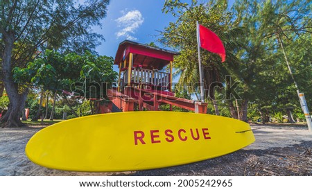 Red Lifeguard tower and yellow rescue board with red warning flag landscape wide shot