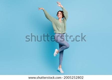 Full length photo of sweet adorable young lady wear green cardigan dancing isolated blue color background