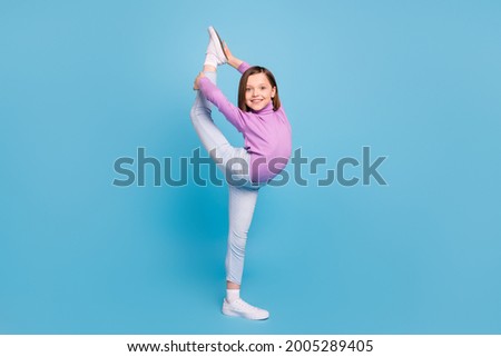 Full length body size little girl practising stretching isolated pastel blue color background