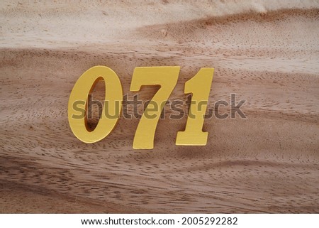 Gold Arabic numerals 071 on a dark brown to off-white wood pattern background.