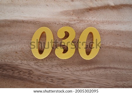 Gold Arabic numerals 030 on a dark brown to off-white wood pattern background.