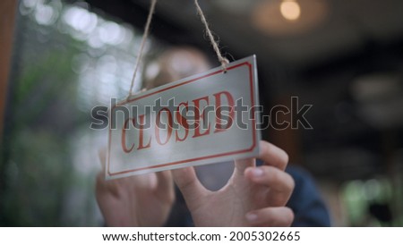 Soft focus, View through window, Close up hand of  Handsome young man owner hanging storefront sign to close at cafe or restaurant, small business service concept