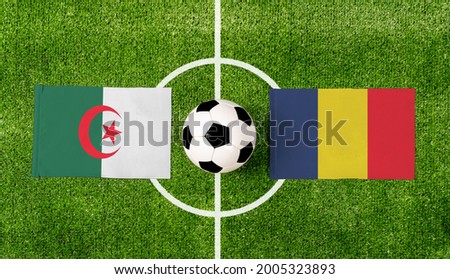 Top view soccer ball with Algeria vs. Chad flags match on green football field.