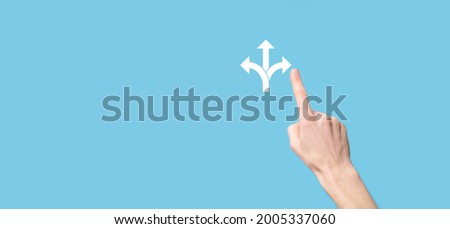 Male hand holding icon with three directions icon on blue background.n doubt, having to choose between three different choices indicated by arrows pointing in opposite direction concept. three ways