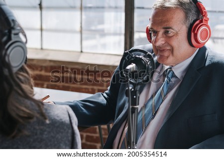 Broadcaster interviewing a guest in a studio