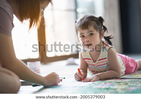 cute baby girl painting with her mother at the house