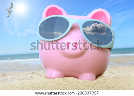 Pink piggy bank on a beach with sunglasses