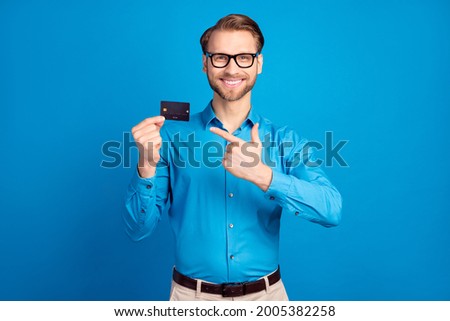 Photo of young excited man happy positive smile point finger bank card ads advise recommend isolated over blue color background