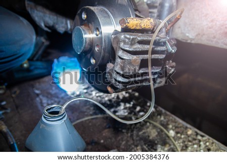 bleeding the brake hydraulic system, hose from the caliper, changing the brake fluid. Royalty-Free Stock Photo #2005384376