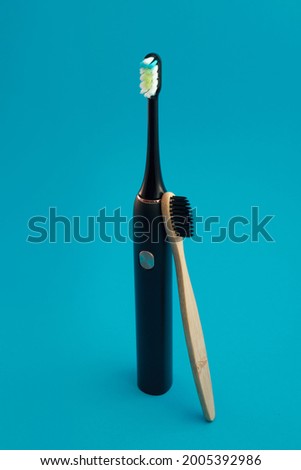 Electric and wooden toothbrush on blue background