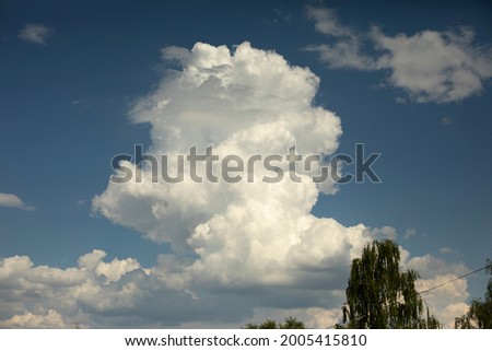 A giant cloud in the sky. The white cloud flies through the atmosphere. Summer weather. Beauty in heaven.