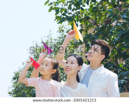 A happy family of three throwing paper airplanes outdoors high quality photo