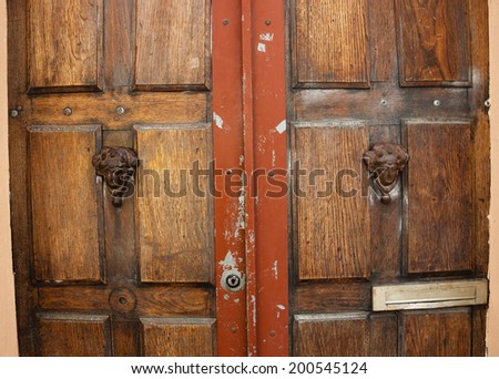 Weathered wooden door with decorative handles - in shape of human head with wreath on it (like Roman patrician). Paris, France. 