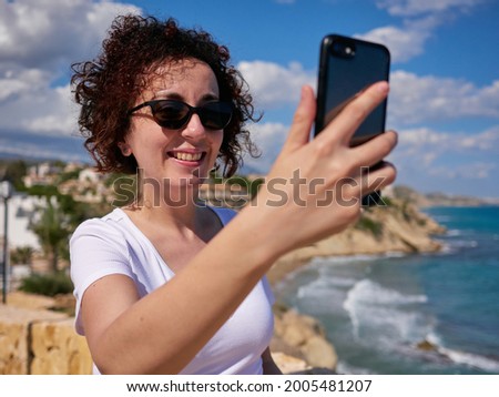 Woman taking a selfie with the mobile with the sea in the background
