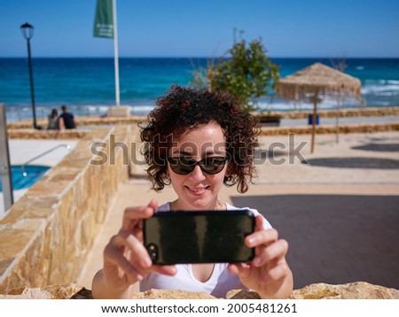 Woman taking a selfie next to a beach hut